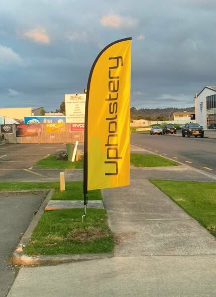The bright yellow All Upholstery flag on the street in Whakatane